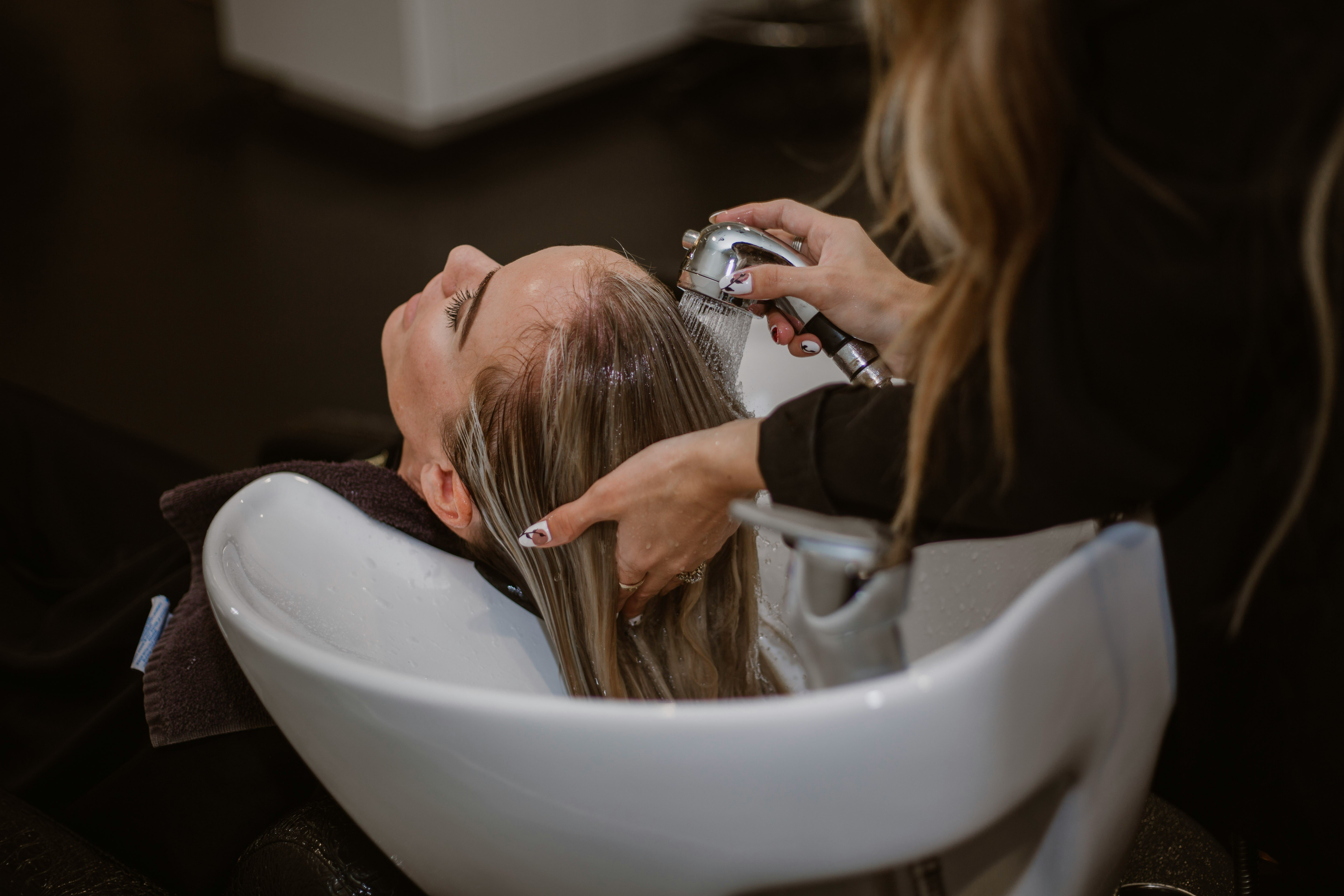 A woman getting her hair cut by a stylist in a salon, representing WordPress salon booking plugins