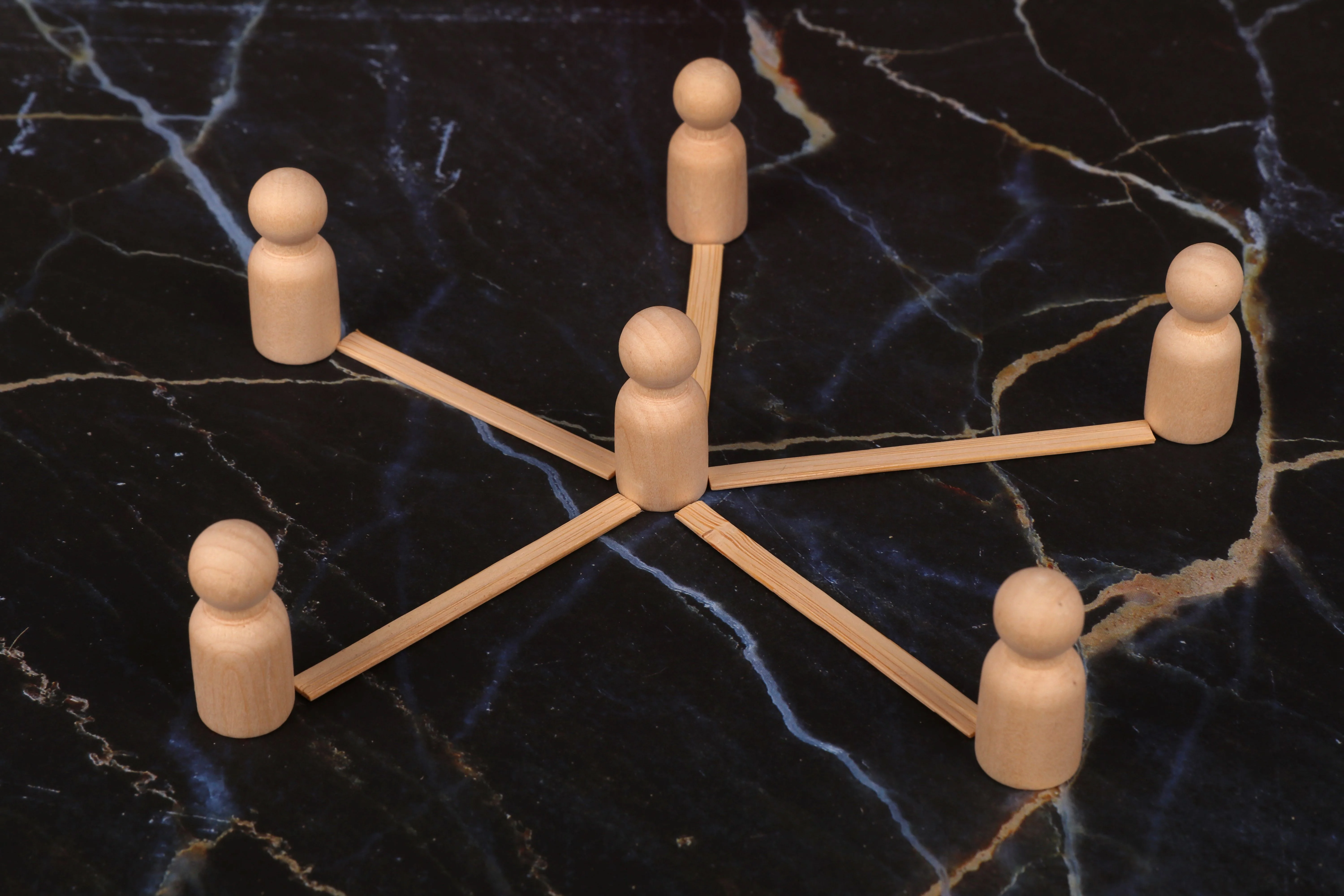 Wooden figures arranged in a network pattern, symbolizing community connection