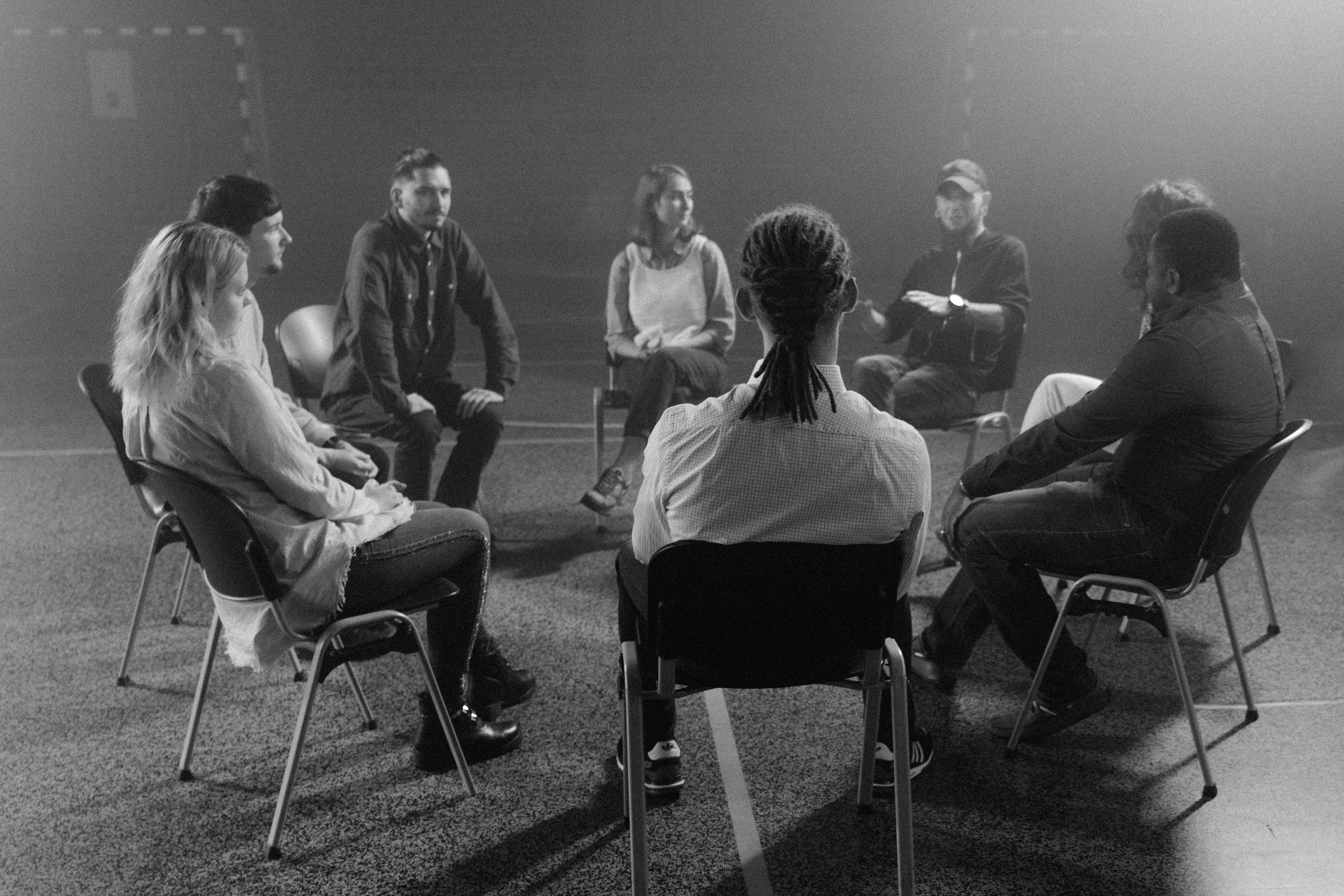 A diverse group of people sitting in a circle, supporting and talking with each other