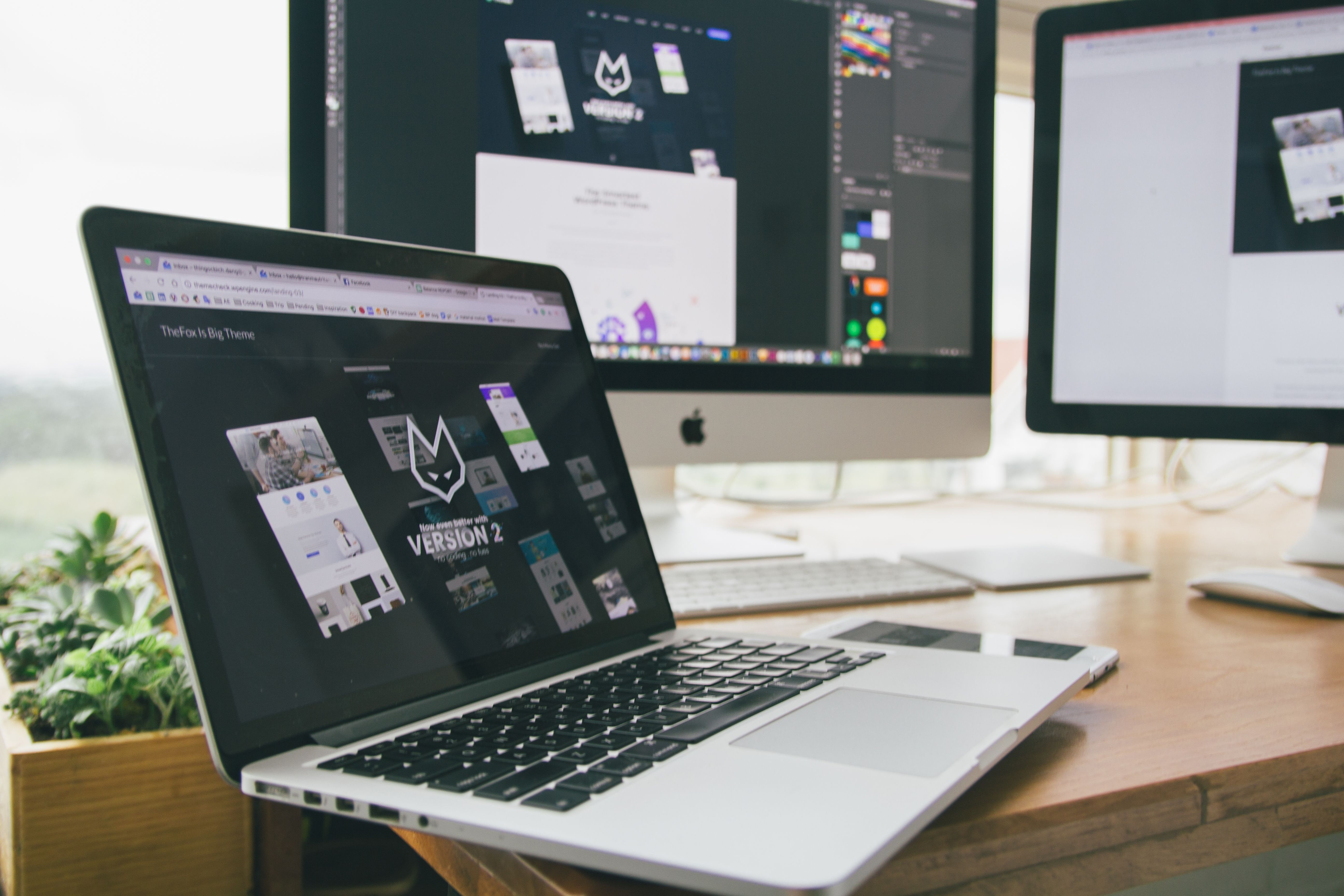 Website design workspace with laptop and monitors